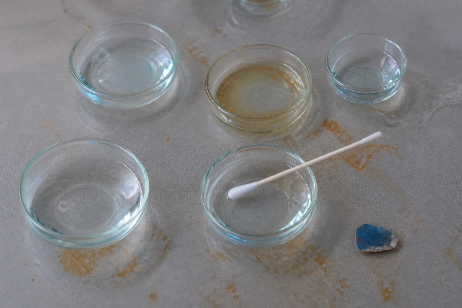 Small glass dishes and cotton swab on a matte conservation table